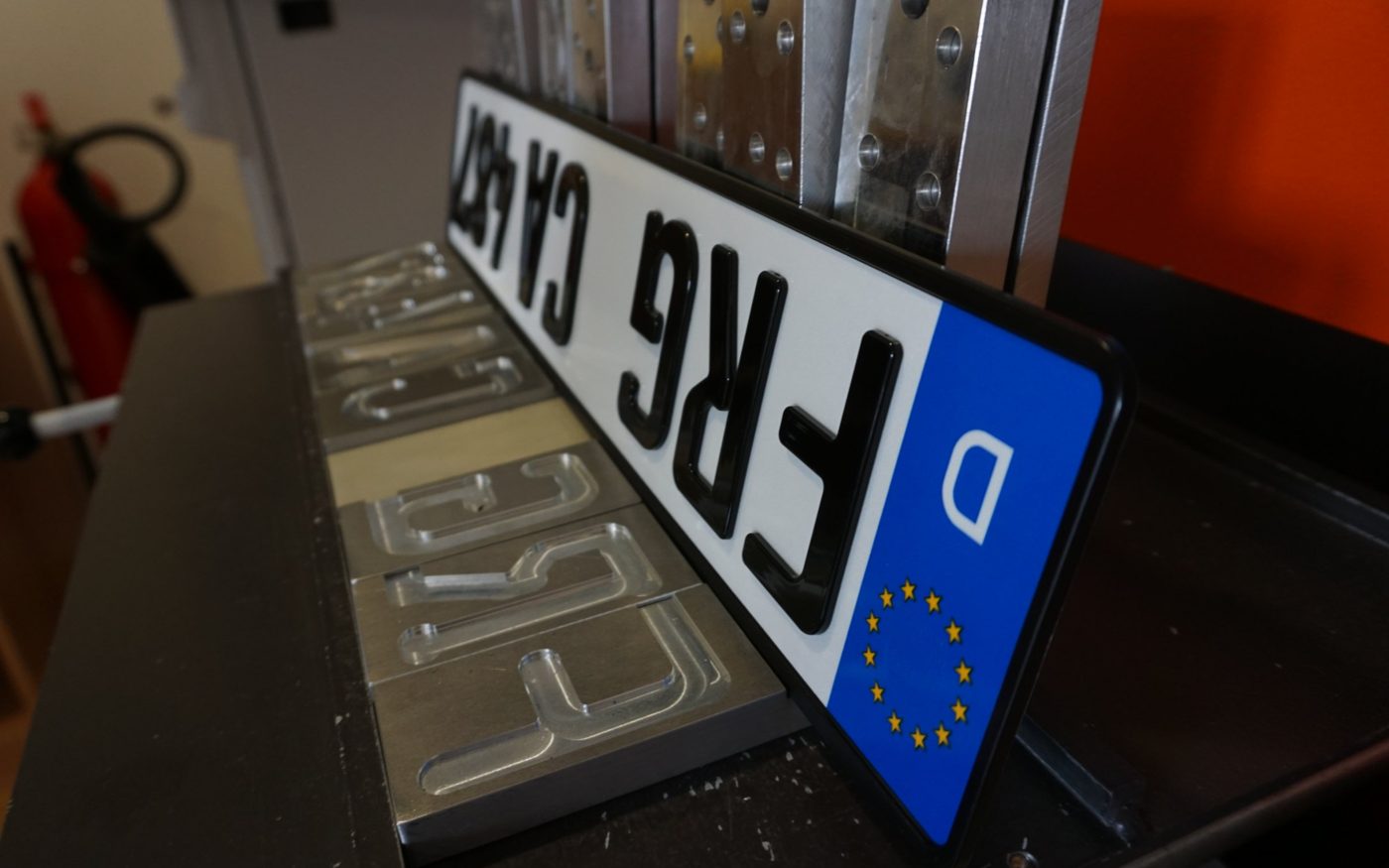 Fertig gesteckprägtes 3D Kennzeichen vor den leeren Aussparungen des Prägewerkzeugs